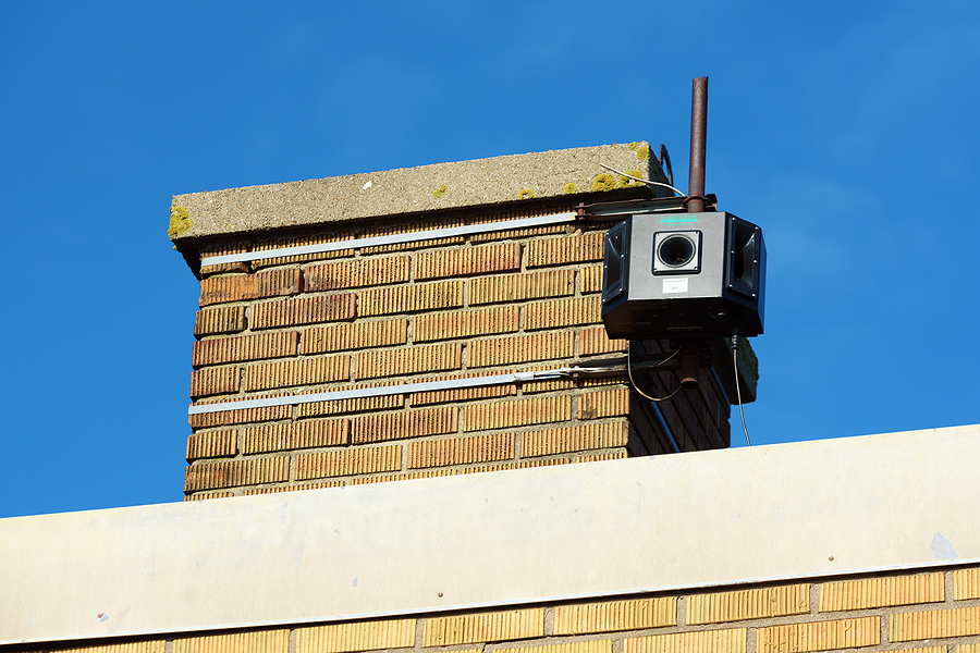 A loudspeaker mounted to a chimney to keep raccoons away